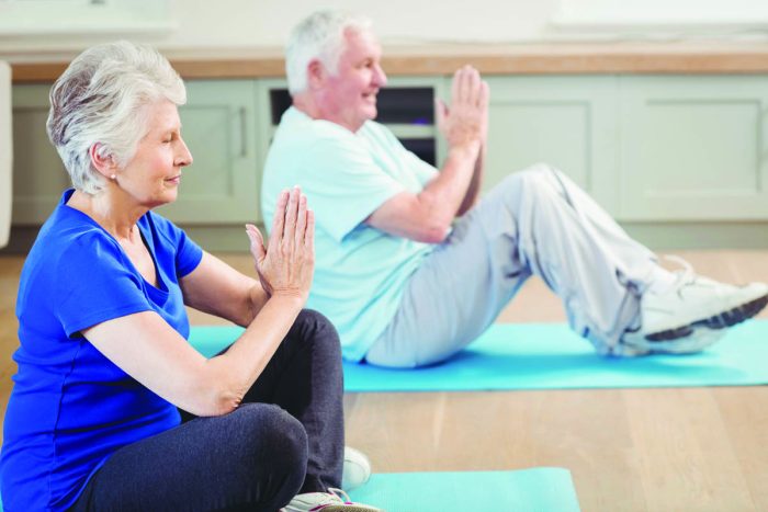 Senior couple performing yoga exercise at home Senior couple performing yoga exercise at home